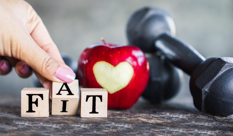 hand flipping fat to fit word with red apple and dumbbells ,heal